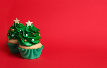 Christmas tree shaped cupcakes on red background. Space for text