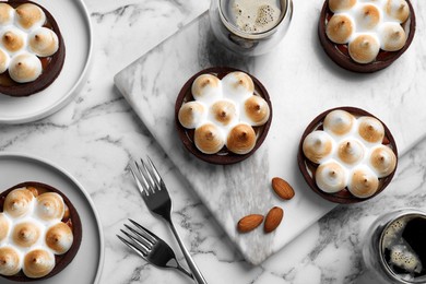 Delicious salted caramel chocolate tarts with meringue and coffee on white marble table, flat lay