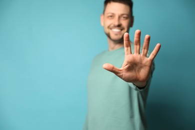 Left-handed man against light blue background, focus on palm. Space for text