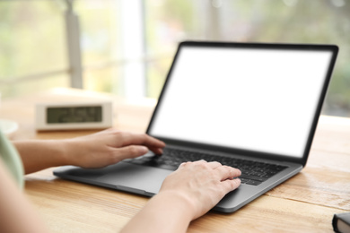 Woman working with modern laptop at wooden table, closeup. Space for design
