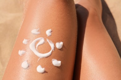 Sun drawn with sunscreen on woman's leg at beach, closeup