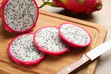 Photo of Delicious cut white pitahaya fruit and knife on wooden board, closeup