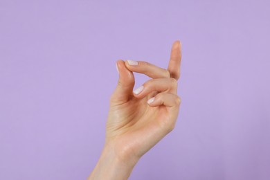 Woman snapping fingers on violet background, closeup of hand