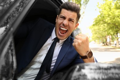 Emotional man yelling in car. Aggressive driving behavior