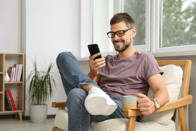 Happy handsome man using smartphone at home