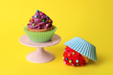 Dropped and good cupcakes on yellow background. Troubles happen