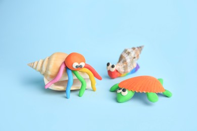 Photo of Turtle, snail and crab made from plasticine on light blue background. Children's handmade ideas