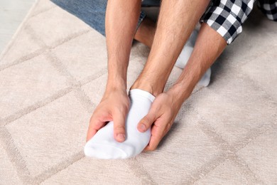 Man rubbing sore foot at home, closeup