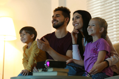Happy family watching movie using video projector at home