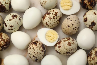 Photo of Unpeeled and peeled hard boiled quail eggs on light table, flat lay