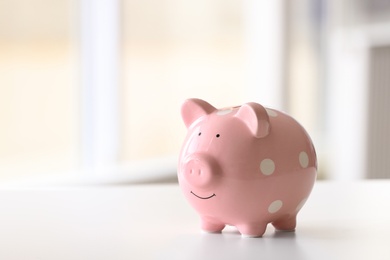 Piggy bank on table against blurred background. Space for text