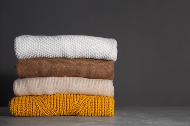 Stack of folded knitted sweaters on grey background