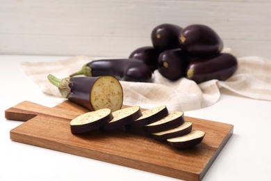 Photo of Cut and whole raw ripe eggplants on white table