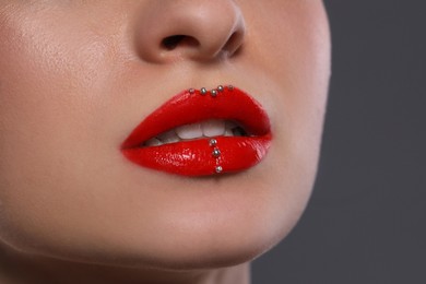 Young woman with red lips makeup on grey background, closeup