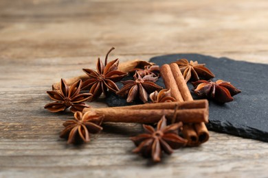 Aromatic cinnamon sticks and anise stars on wooden table, closeup