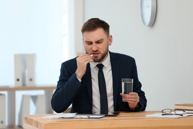 Man taking pill against migraine in office