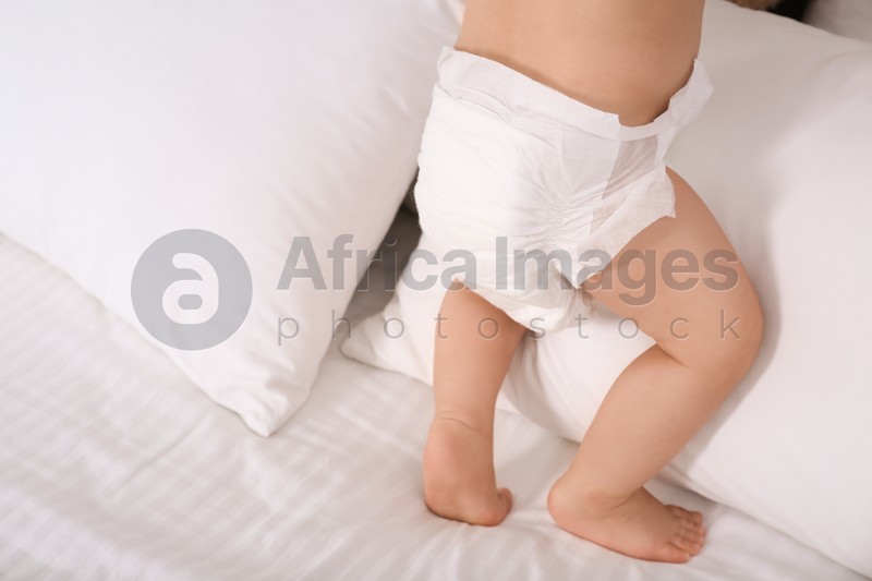 Cute baby in dry soft diaper on white bed, closeup