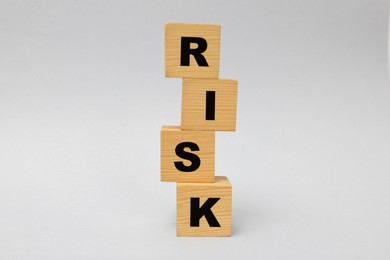 Stack of wooden cubes with word Risk on light grey background