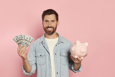 Happy man with money and piggy bank on pale pink background