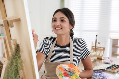 Young woman drawing on easel with brush, closeup