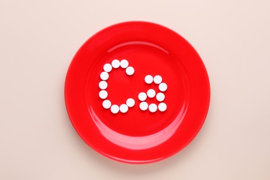 Plate with calcium symbol made of white pills on beige background, top view