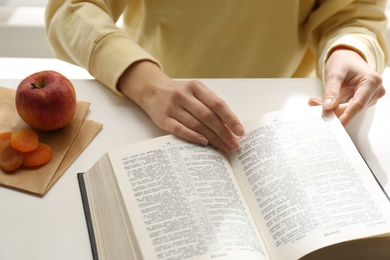 Woman with Holy Bible at white table indoors, closeup. Great Lent season
