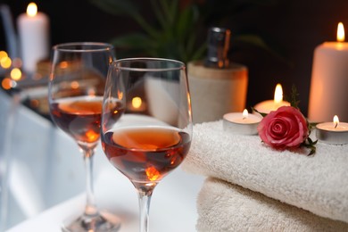 Wine in glasses and rose on edge of bath indoors, closeup. Romantic atmosphere