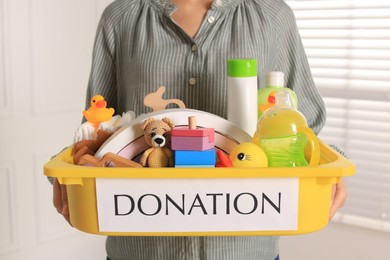 Woman holding donation box with child goods indoors, closeup
