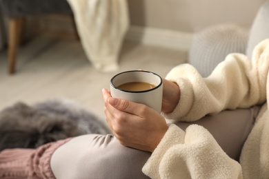 Woman with cup of hot drink resting at home, closeup