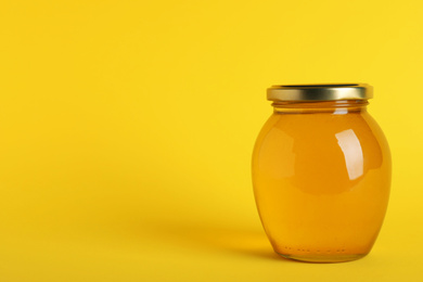 Jar of organic honey on yellow background. Space for text