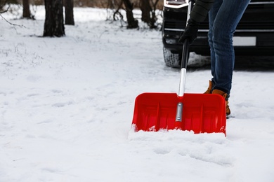 Man removing snow with shovel near car outdoors on winter day, closeup