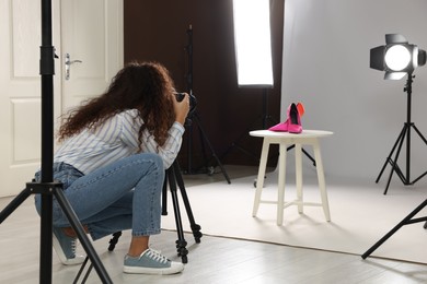 Photo of Professional photographer taking picture of stylish shoes in studio