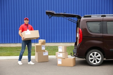 Courier loading packages in car trunk outdoors