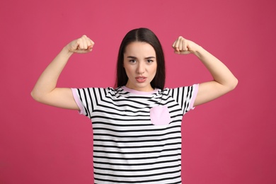 Strong woman as symbol of girl power on pink background. 8 March concept