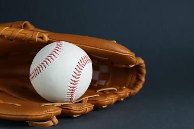 Photo of Catcher's mitt and baseball ball on dark background, closeup with space for text. Sports game