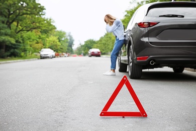 Emergency stop sign and woman near broken car on background