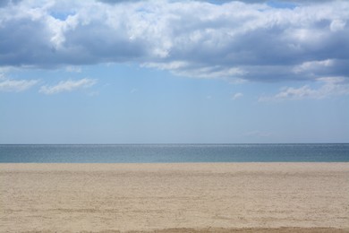 Picturesque view of sandy beach near calm sea on cloudy day