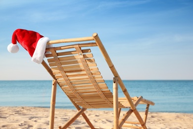 Photo of Sun lounger with Santa's hat on beach. Christmas vacation