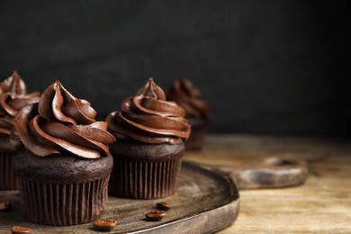 Delicious chocolate cupcakes with cream on wooden table. Space for text