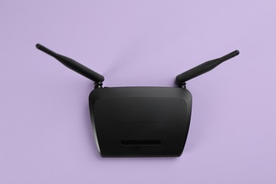 Modern Wi-Fi router on lilac background, top view