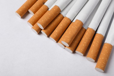 Pile of cigarettes with orange filters on white background, above view. Space for text