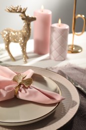 Stylish table setting with pink fabric napkin, beautiful decorative ring and festive decor on white background, closeup