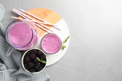 Delicious blackberry smoothie and berries on white table, top view. Space for text