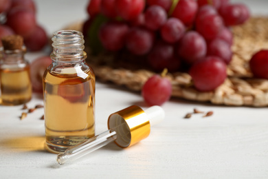 Bottle of natural grape seed oil on white wooden table. Organic cosmetic