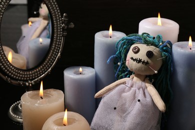 Voodoo doll pierced with pins and candles on black background. Curse ceremony