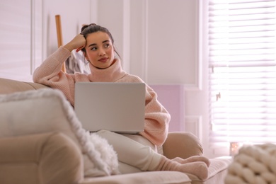 Photo of Beautiful young woman with laptop relaxing at home. Cozy atmosphere
