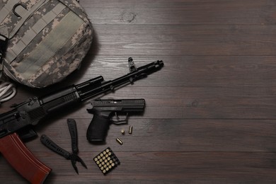 Flat lay composition with guns and military knapsack on wooden table. Space for text