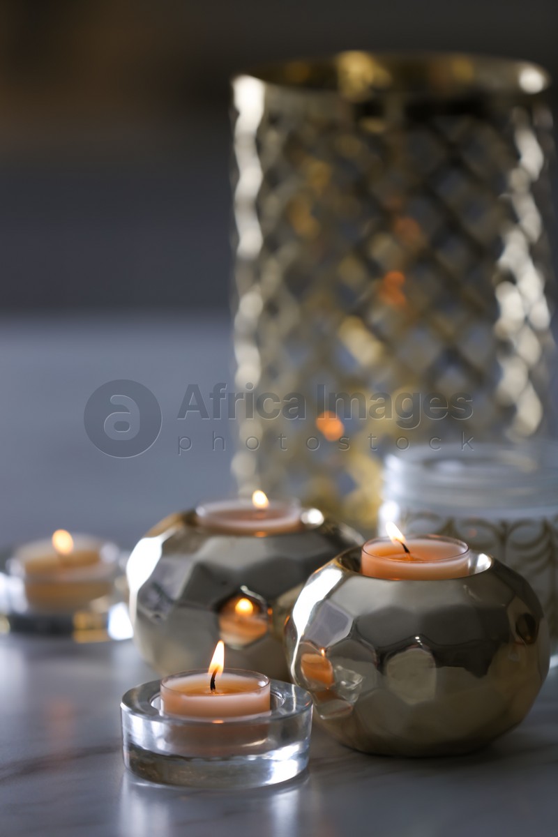 Burning candles in holders on white marble table indoors