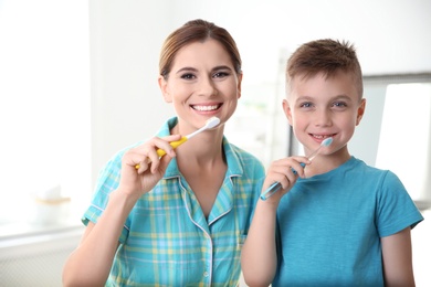 Portrait of mother and her son with toothbrushes in bathroom. Personal hygiene