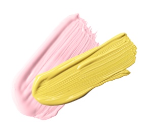 Strokes of pink and yellow color correcting concealers on white background, top view
